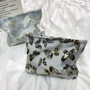 Detailed embroidery of butterfly patterns on small fabric cosmetic travel pouches