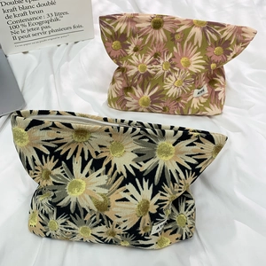 Detail of floral corduroy makeup bags with vintage daisy patterns and smooth metal zippers