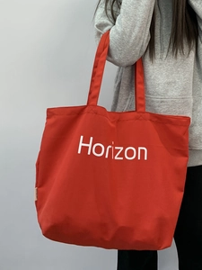 Detail of a large red canvas tote bag with white Horizon lettering on the front