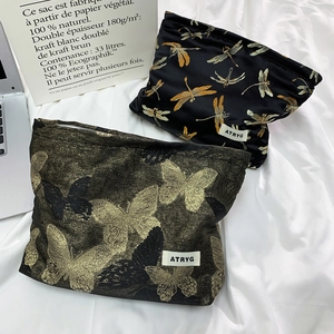 Detail of embroidered dragonfly and butterfly jacquard patterns on luxury makeup bags