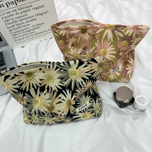 Detail of floral knit cosmetic bags with daisy patterns and textured zipper closures