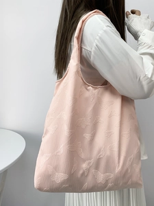 Pink shoulder tote bag with butterfly embroidery texture shown on a female model