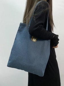 Side view of a person wearing a blue denim tote bag with cute bear embroidery detail