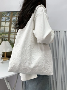 Detail of white tote bag with embossed rose floral texture and soft knitted fabric
