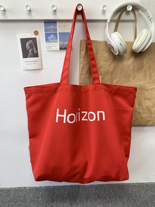 Detail of red canvas tote bag with Horizon logo hanging in a minimalist studio setting