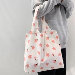 Detailed side view of a large white canvas tote bag with fresh pink floral patterns