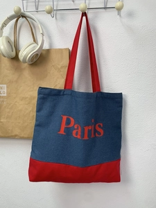 Minimalist denim tote bag with Paris print and red handles in a stylish wall hanging view