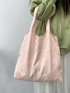 Detail of light pink tote bag featuring 3D butterfly embossed texture and wide strap