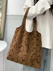 Detail of elegant brown tote bag featuring 3D embossed rose textures and soft shoulder strap