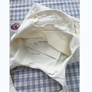 Vue détaillée du sac en toile brodé de marguerites blanches avec poche zippée