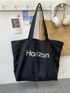 Detail of a black canvas tote bag with Horizon text print in a casual lifestyle setting