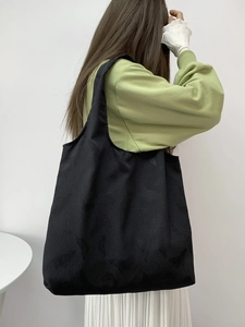 Close-up of black tote bag featuring subtle butterfly embossed texture and large capacity