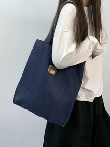 Close-up of cute teddy bear embroidery on a durable dark blue denim tote bag for students