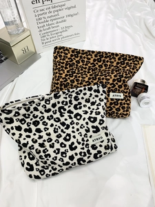 Detailed close-up of leopard print canvas makeup bags on white fabric with beauty products