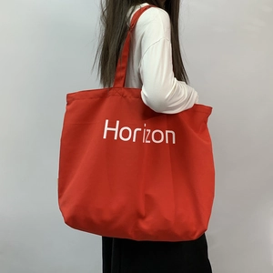 Detail of red canvas tote bag with Horizon print being worn by a model in a side view