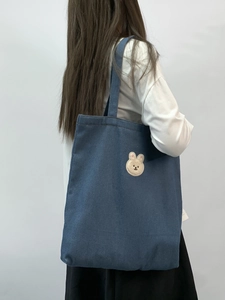 Detailed view of deep blue denim tote bag with cute rabbit embroidery and long handles