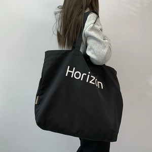 Detail of black canvas tote bag with Horizon print being worn as a crossbody messenger bag