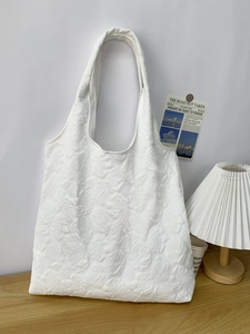 Close-up of white tote bag featuring 3D embossed rose floral texture and fabric details