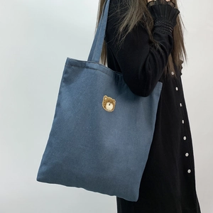 Detail of blue denim tote bag featuring a cute 3D brown teddy bear embroidery on the front