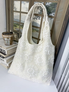 Gros plan détaillé sur la broderie de marguerites 3D du sac cabas en toile beige