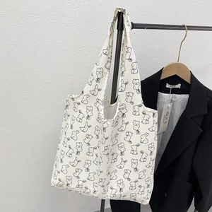 Detailed close-up of a white canvas tote bag featuring black cartoon bunny line art patterns