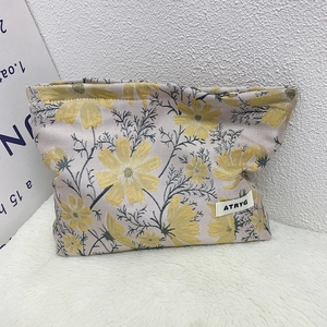 Close-up of jacquard fabric texture and yellow daisy floral pattern on travel cosmetic bag