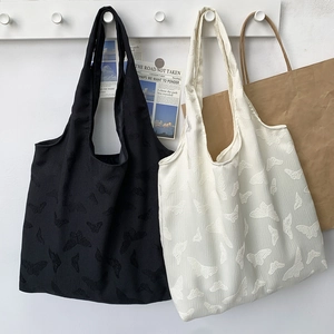 Detail view of butterfly embossed texture on black and cream white large canvas tote bags