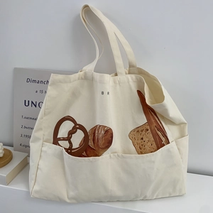 Detail of canvas tote bag with bread prints and a side pocket in a minimalist setting