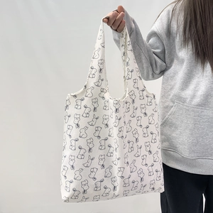 Detailed view of canvas tote bag with black cartoon rabbit print and shoulder straps