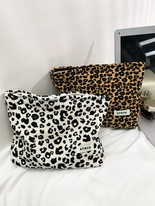 Detailed close-up of leopard print canvas makeup bags with zip closure and woven label