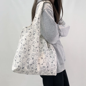 Close-up of minimalist white canvas tote bag with playful black rabbit print patterns
