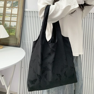 Close-up of black tote bag with embossed butterfly texture and minimalist structure