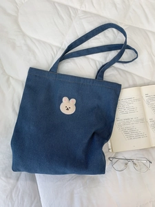 Detail of cute embroidered bear patch on high-quality navy blue denim shoulder tote bag