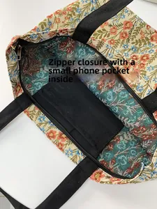 Detail of floral tote bag showing metal zipper closure and interior phone pocket