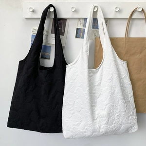Close-up of elegant tote bags with 3D floral embossed texture in black and white colors