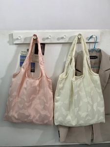 Close-up of butterfly lace texture on canvas tote bags in pink and cream colors