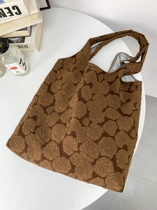 Detail of deep brown tote bag featuring rose embossed texture and floral relief pattern