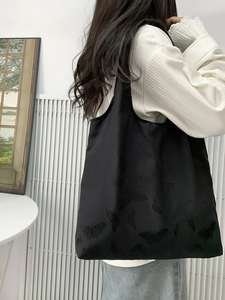 Close-up of black oversized tote bag with butterfly textured jacquard fabric on shoulder