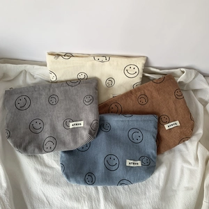 Close-up of corduroy toiletry bags with zipper and smiley face pattern in four colors