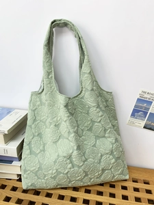 Close-up of a light green tote bag featuring an elegant 3D rose embossed texture and knit fabric