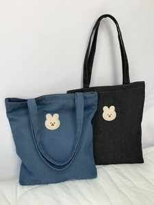 Detail of denim tote bags with cute cartoon rabbit embroidery in blue and grey