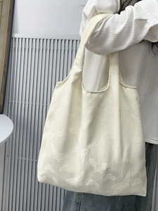 Detail showing the embossed butterfly texture on the cream-white knit shoulder tote bag