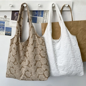 Detail of embossed rose texture on khaki and white tote bags with wide shoulder straps