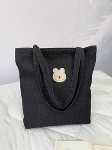 Close-up of deep blue denim tote bag featuring cute animal embroidery and fabric texture