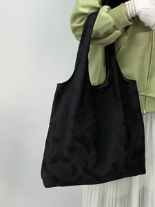 Close-up of black tote bag featuring delicate butterfly embossed texture and durable canvas