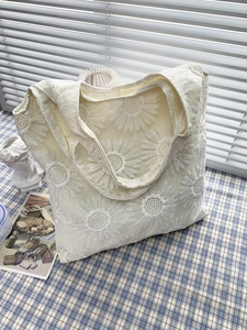 Détail de broderie de tournesol sur un sac cabas en toile crème au style champêtre