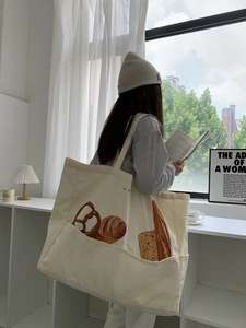 Detailed close-up of ivory canvas tote bag featuring realistic bread illustration print