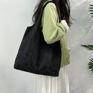 Detail of black tote bag featuring butterfly texture pattern shown on a shoulder