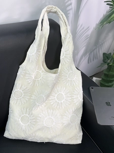 Détail de broderie de tournesol sur un sac cabas en maille crème pour l'été