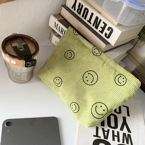 Detailed texture of lime green corduroy makeup bag with black smiley faces in a lifestyle setting